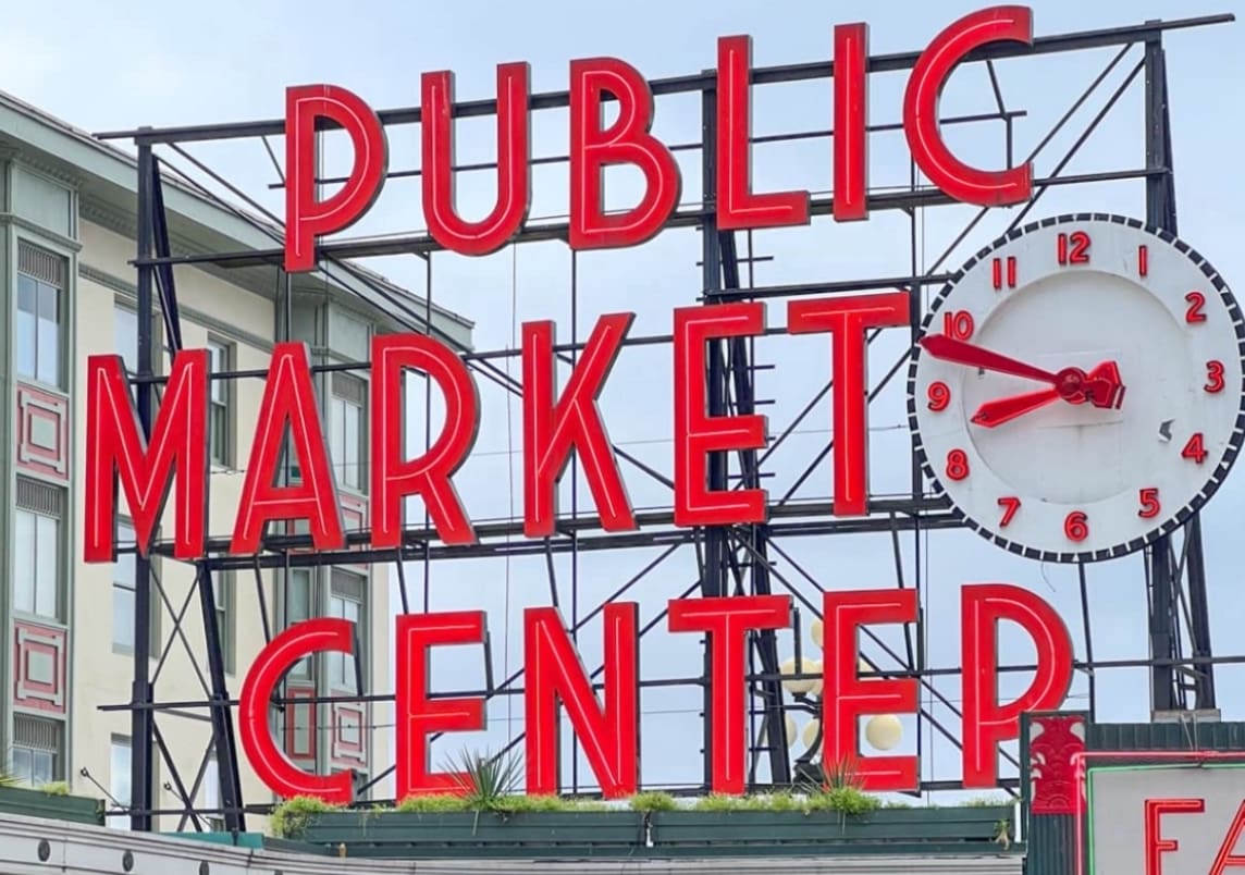 A sign that says public market center with a clock.