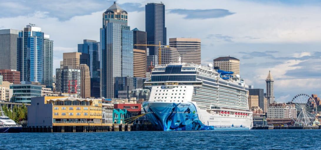 A large cruise ship in the water near some buildings.